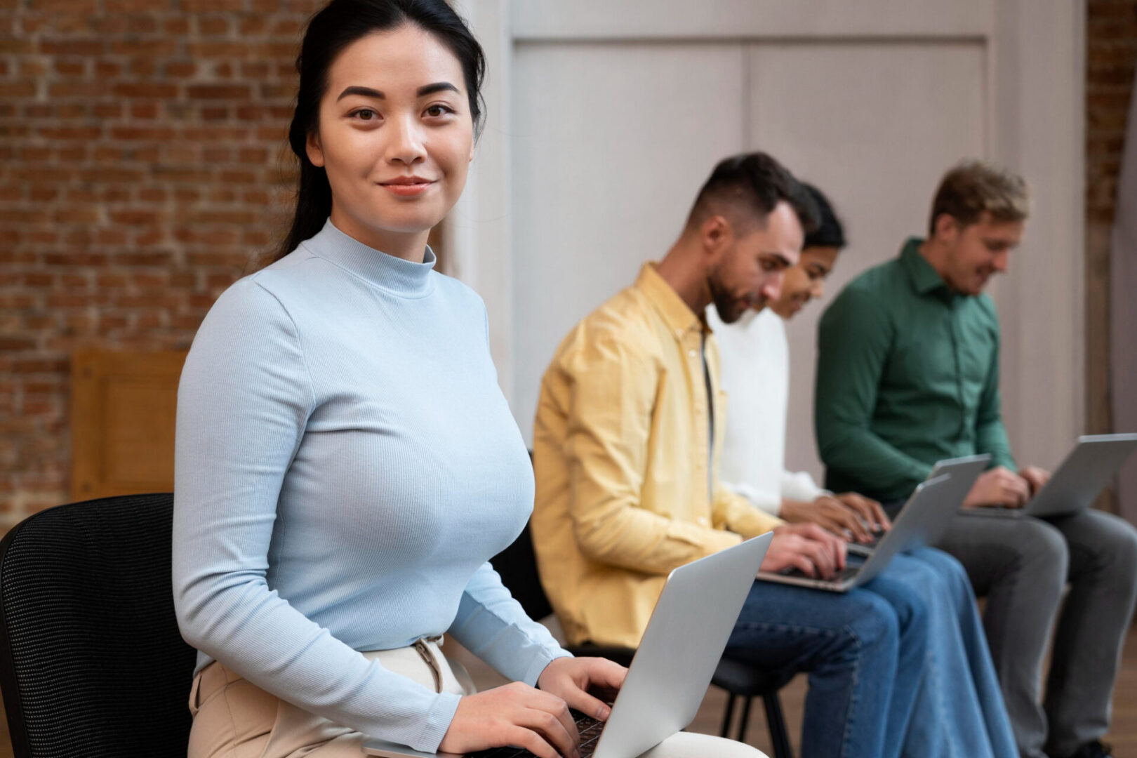 Woman using laptop with colleagues in background